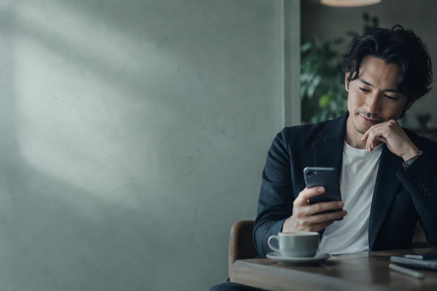 カフェでスマートフォンを見ながら微笑む男性